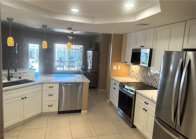 kitchen with white cabinets, hanging light fixtures, sink, appliances with stainless steel finishes, and a tray ceiling