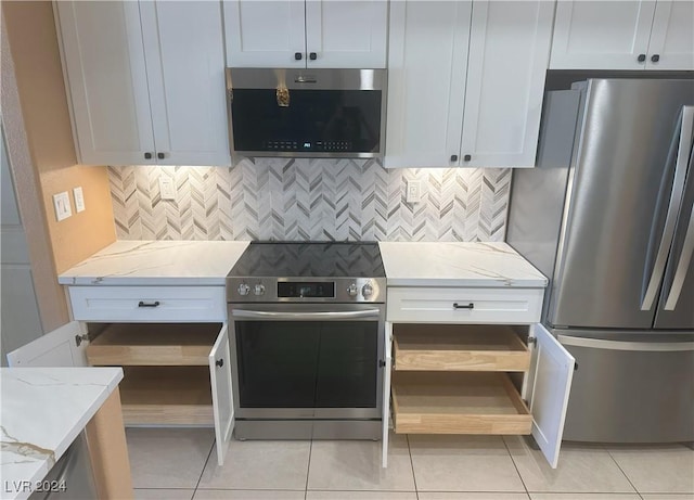 kitchen featuring light stone counters, white cabinets, stainless steel appliances, and light tile patterned floors