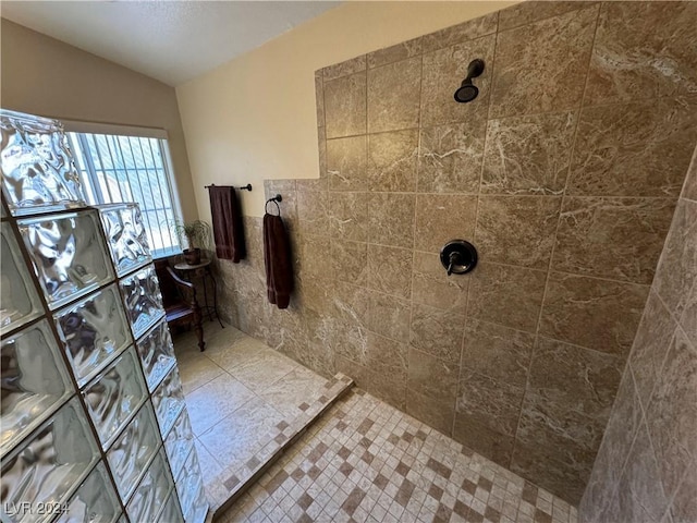 bathroom featuring a tile shower and vaulted ceiling