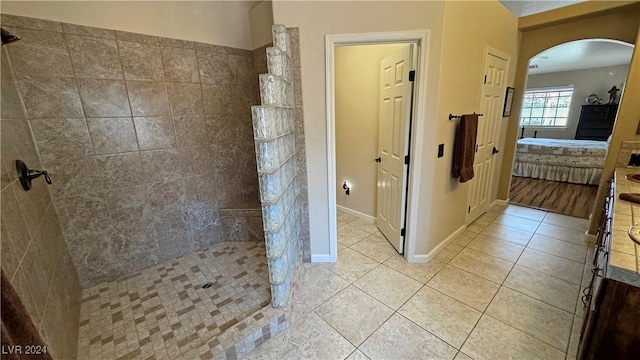 bathroom featuring tile patterned flooring, a tile shower, and vanity