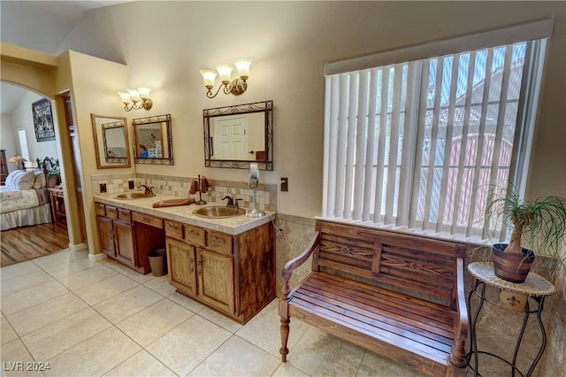 bathroom featuring tile patterned flooring, vanity, tasteful backsplash, and vaulted ceiling