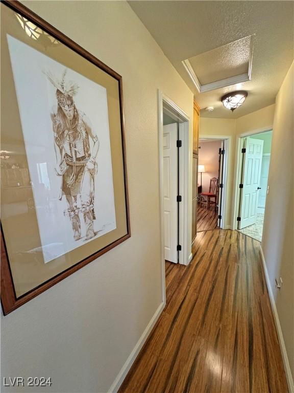 corridor featuring hardwood / wood-style floors, crown molding, and a textured ceiling