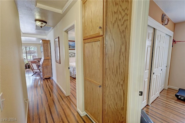 hall with light hardwood / wood-style flooring and a textured ceiling