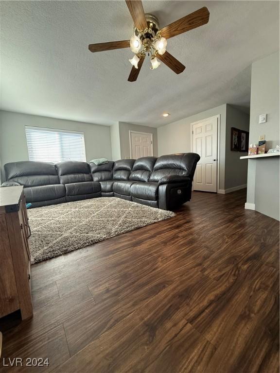 living room featuring a textured ceiling, dark hardwood / wood-style floors, and ceiling fan