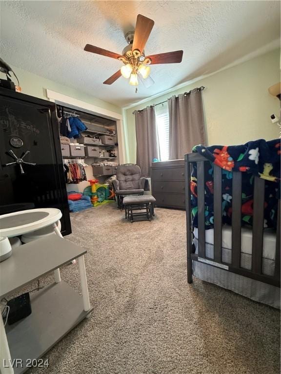 bedroom with ceiling fan, carpet floors, and a textured ceiling