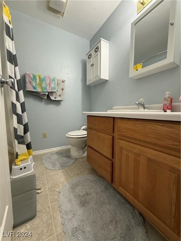 bathroom featuring tile patterned flooring, vanity, and toilet