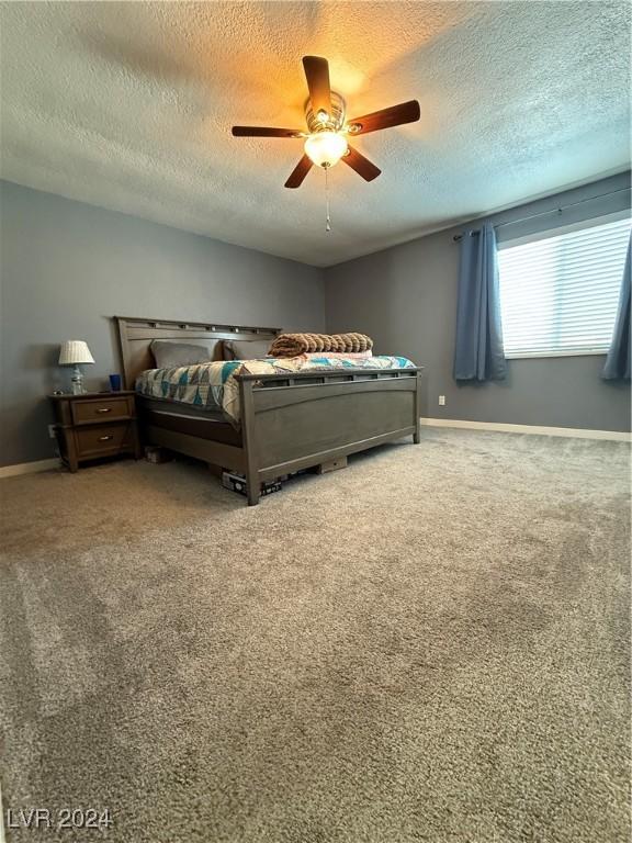 carpeted bedroom featuring ceiling fan and a textured ceiling