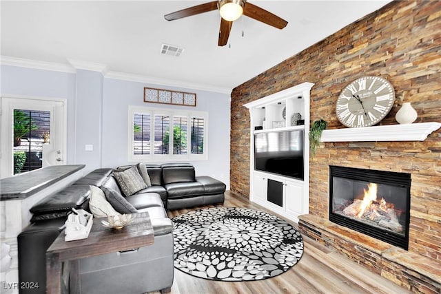 living room featuring plenty of natural light, crown molding, wood-type flooring, and a fireplace