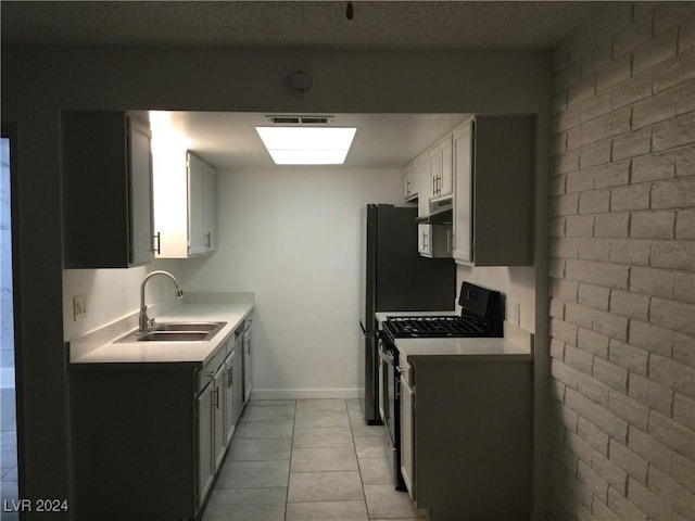 kitchen featuring a sink, brick wall, appliances with stainless steel finishes, under cabinet range hood, and visible vents