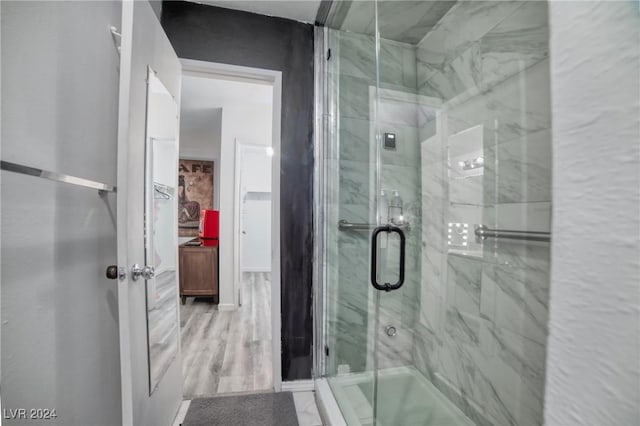 bathroom featuring wood-type flooring and an enclosed shower