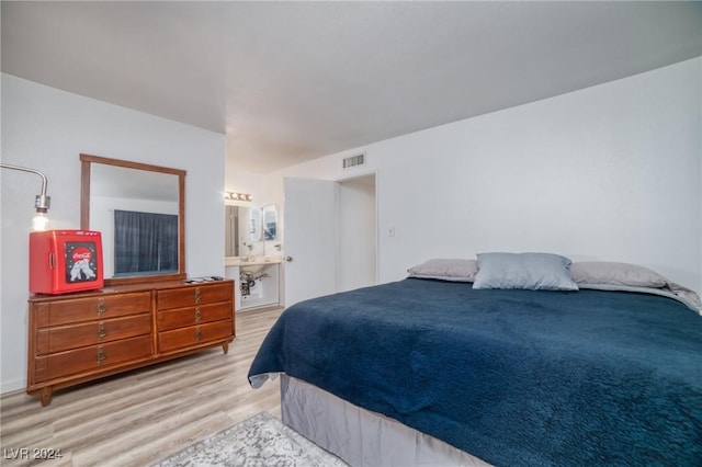 bedroom with ensuite bathroom and light hardwood / wood-style floors