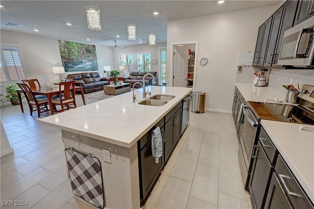 kitchen featuring sink, ceiling fan, an island with sink, appliances with stainless steel finishes, and decorative light fixtures