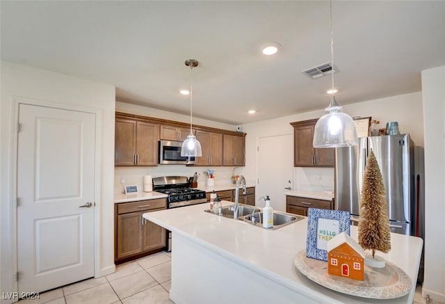 kitchen featuring sink, decorative light fixtures, a kitchen island with sink, light tile patterned floors, and appliances with stainless steel finishes