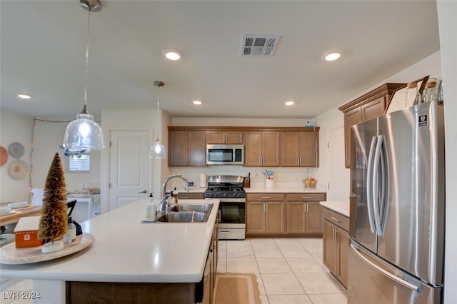 kitchen featuring sink, hanging light fixtures, stainless steel appliances, a center island with sink, and light tile patterned flooring