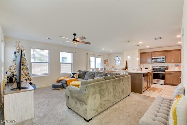 carpeted living room featuring ceiling fan and sink