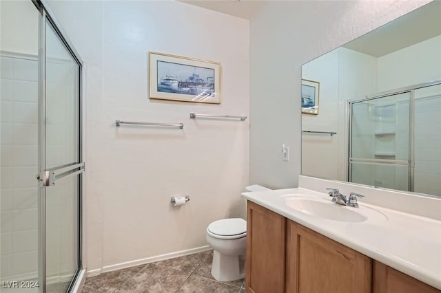 bathroom with tile patterned floors, vanity, toilet, and a shower with door