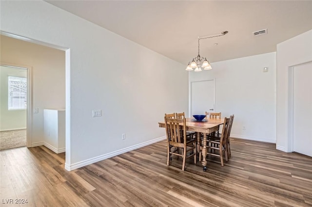 dining area with hardwood / wood-style floors and a notable chandelier