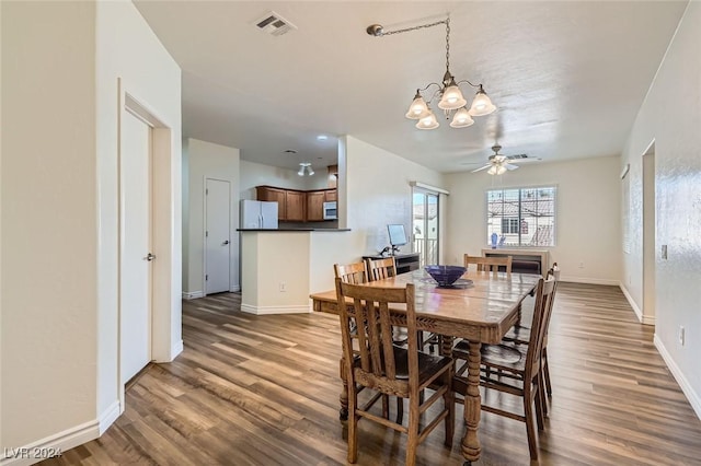 dining space with ceiling fan with notable chandelier and dark hardwood / wood-style floors