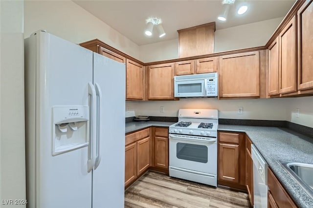 kitchen with light wood-type flooring, white appliances, and sink