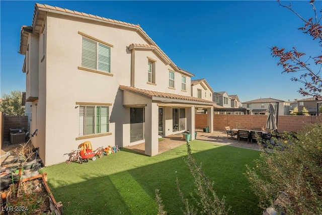 rear view of property featuring a patio, a yard, and cooling unit