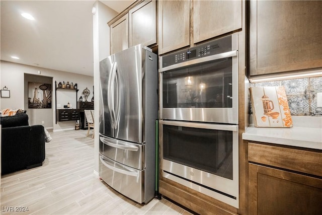 kitchen featuring stainless steel appliances, light hardwood / wood-style flooring, and decorative backsplash