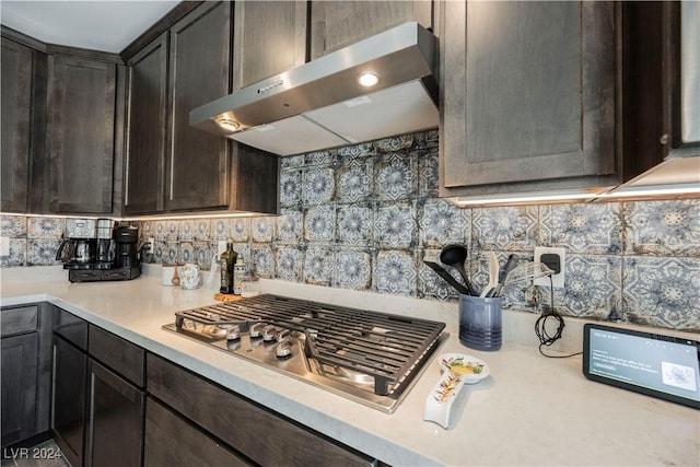 kitchen with dark brown cabinets, stainless steel gas cooktop, decorative backsplash, and wall chimney range hood