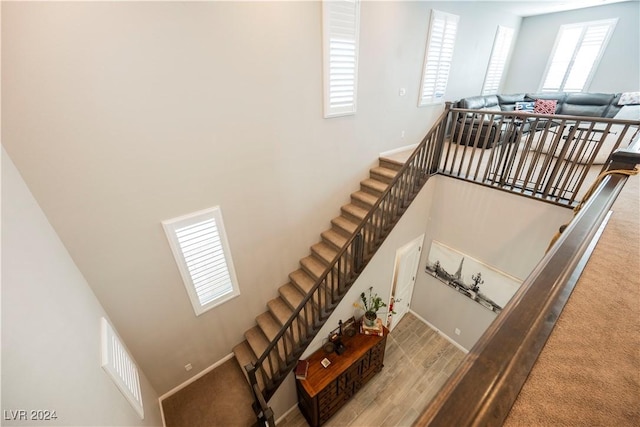 staircase featuring a towering ceiling and wood-type flooring