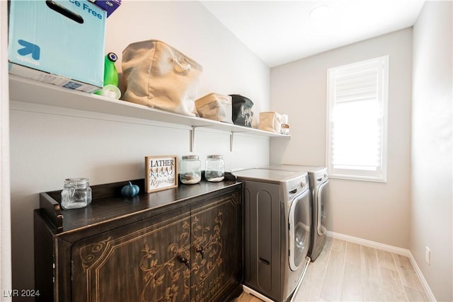 washroom with washing machine and clothes dryer and light hardwood / wood-style flooring