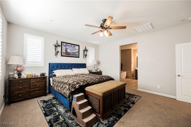 bedroom featuring ceiling fan, ensuite bathroom, light carpet, and multiple windows