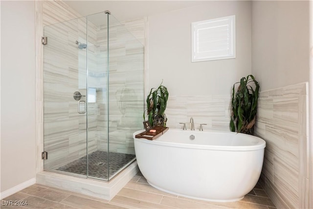 bathroom with separate shower and tub and tile walls