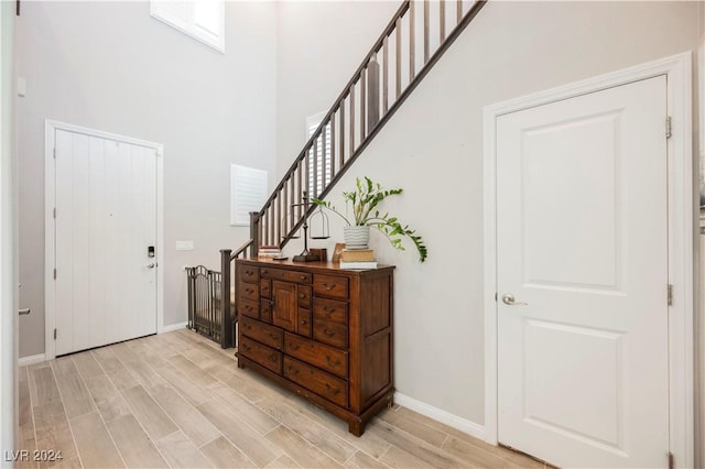 entryway featuring a towering ceiling and light hardwood / wood-style floors