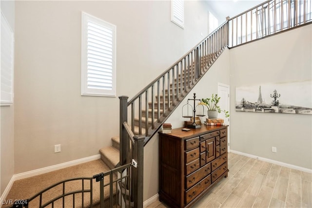 stairs with a towering ceiling and wood-type flooring