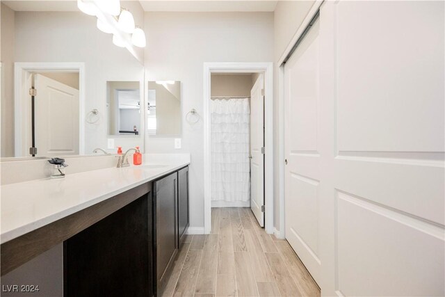 bathroom with hardwood / wood-style flooring, vanity, walk in shower, and a notable chandelier