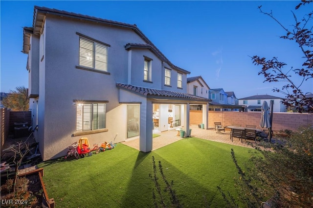 back of property with a yard and a patio