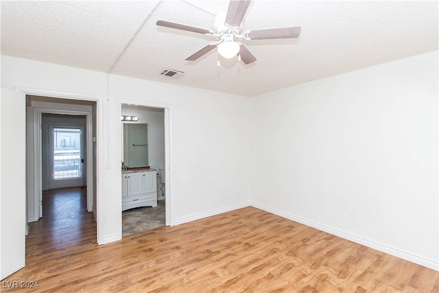 unfurnished room featuring ceiling fan, light wood-type flooring, and a textured ceiling