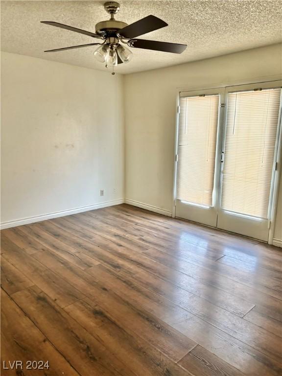 empty room with a textured ceiling, dark hardwood / wood-style floors, and ceiling fan