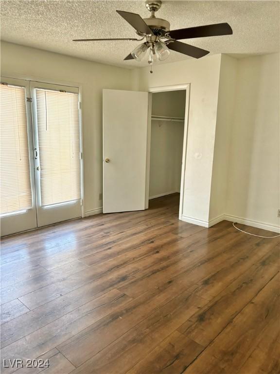 unfurnished bedroom with a textured ceiling, dark hardwood / wood-style flooring, a closet, and ceiling fan