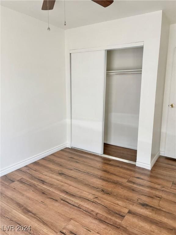 unfurnished bedroom featuring hardwood / wood-style flooring, a closet, and ceiling fan