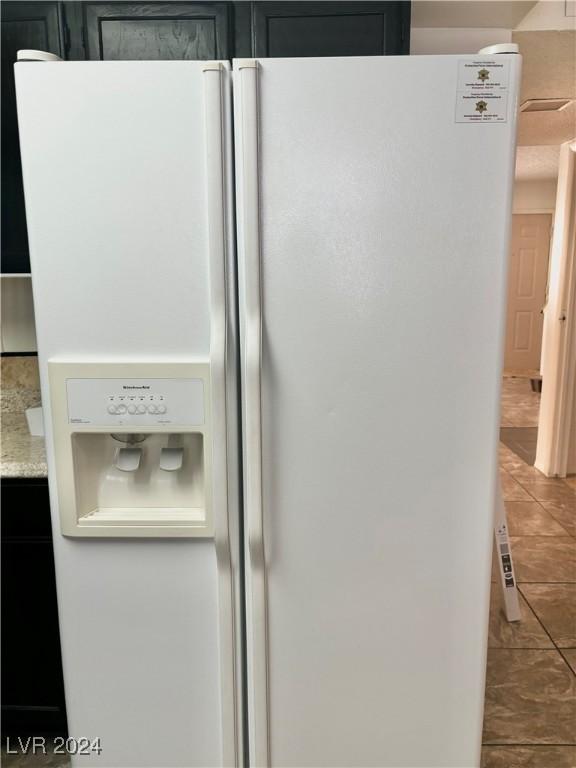details with light stone countertops and white fridge with ice dispenser