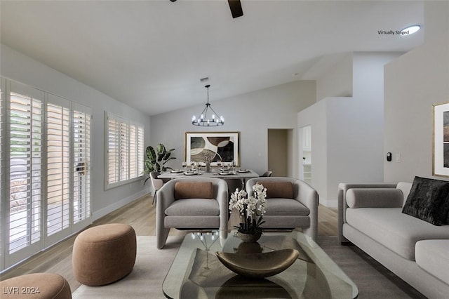 living room featuring light hardwood / wood-style floors, lofted ceiling, and an inviting chandelier