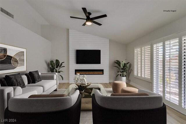 living room with ceiling fan, a large fireplace, lofted ceiling, and light hardwood / wood-style flooring