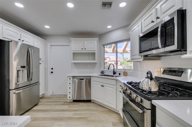 kitchen with sink, white cabinets, light hardwood / wood-style floors, and appliances with stainless steel finishes