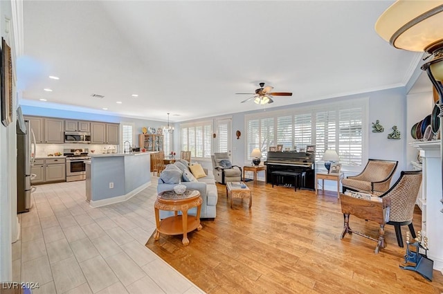 living room with plenty of natural light, ornamental molding, ceiling fan with notable chandelier, and light hardwood / wood-style flooring