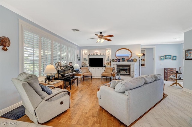 living room with ceiling fan, crown molding, and light hardwood / wood-style floors