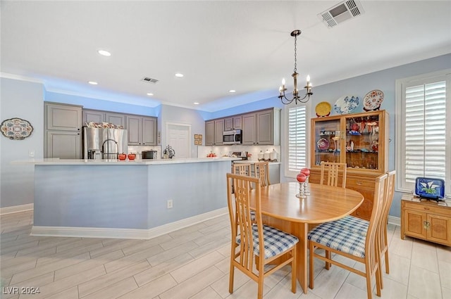 dining space with light hardwood / wood-style flooring, crown molding, and an inviting chandelier