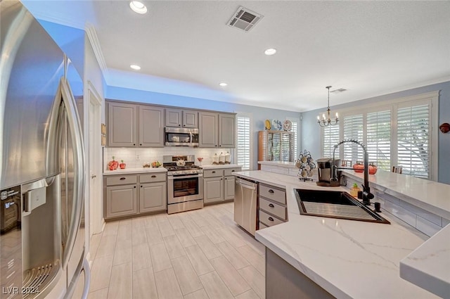 kitchen with a wealth of natural light, sink, decorative light fixtures, and appliances with stainless steel finishes