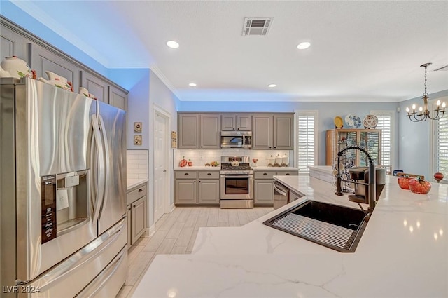 kitchen with gray cabinetry, stainless steel appliances, sink, a notable chandelier, and hanging light fixtures