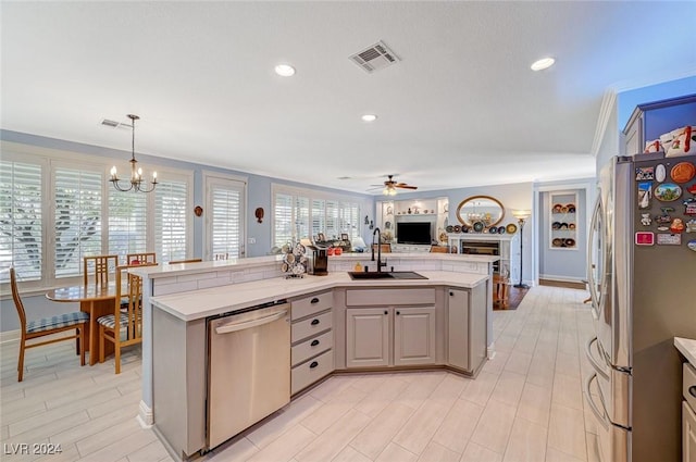 kitchen featuring appliances with stainless steel finishes, decorative light fixtures, a kitchen island with sink, and sink