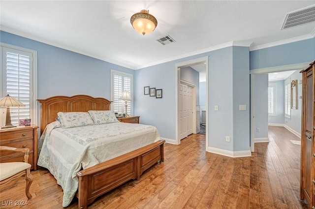 bedroom featuring multiple windows, light hardwood / wood-style flooring, and ornamental molding