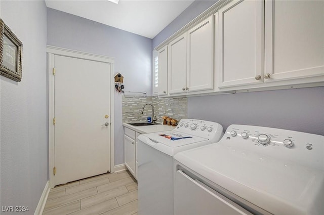 washroom featuring cabinets, washing machine and dryer, sink, and light hardwood / wood-style flooring